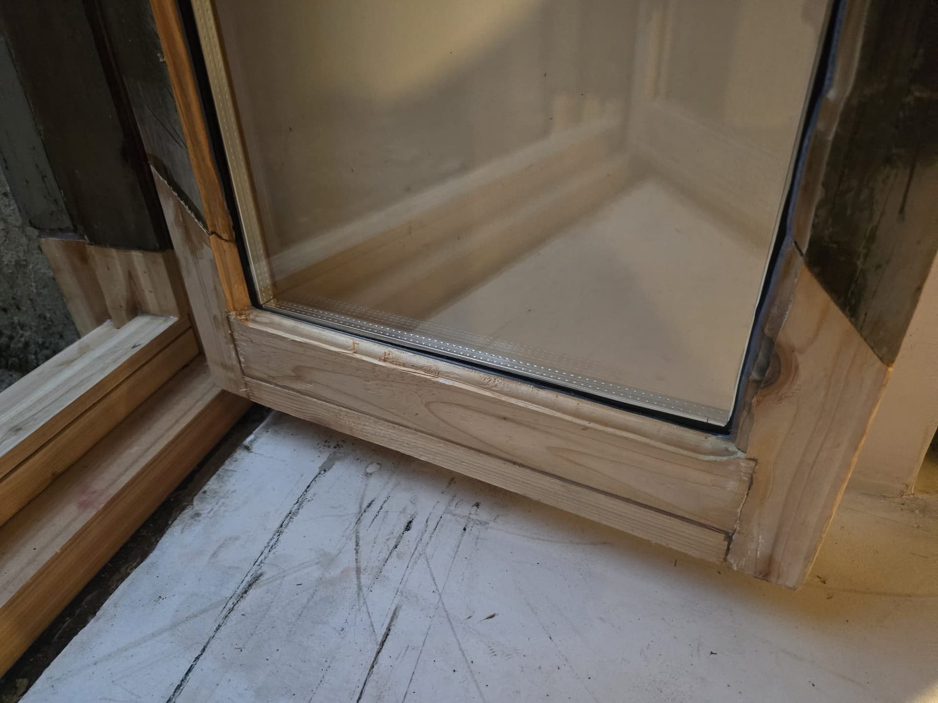 Installation d'une vitre thermos moderne dans un cadre de fenetre en bois restaure